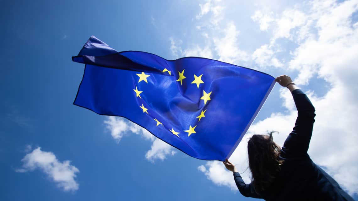 Foto de una mujer ondeando la bandera de la Unión Europea